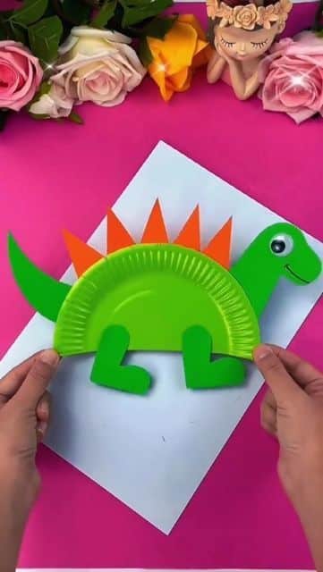 Fun Dinosaur Crafts for Preschoolers_ Creative Classroom Ideas 🦖✨ Colorful dinosaur craft made from paper plates, perfect for a fun children's DIY activity, against a bright pink background. | Sky Rye Design Colorful dinosaur craft made from paper plates, perfect for a fun children's DIY activity, against a bright pink background.