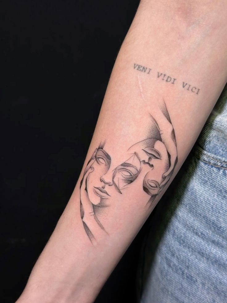 Abstract face line art tattoo on forearm with Veni Vidi Vici text, showcasing minimalist design and artistic detail.