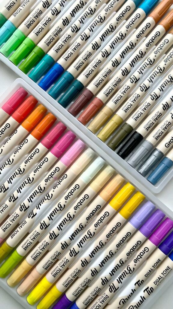 Multicolored dual-tip markers neatly arranged, showcasing a vibrant rainbow palette perfect for art and craft projects.