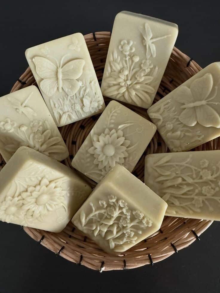 Handmade soaps in a basket featuring intricate floral and butterfly designs, perfect for natural skincare and gift ideas.