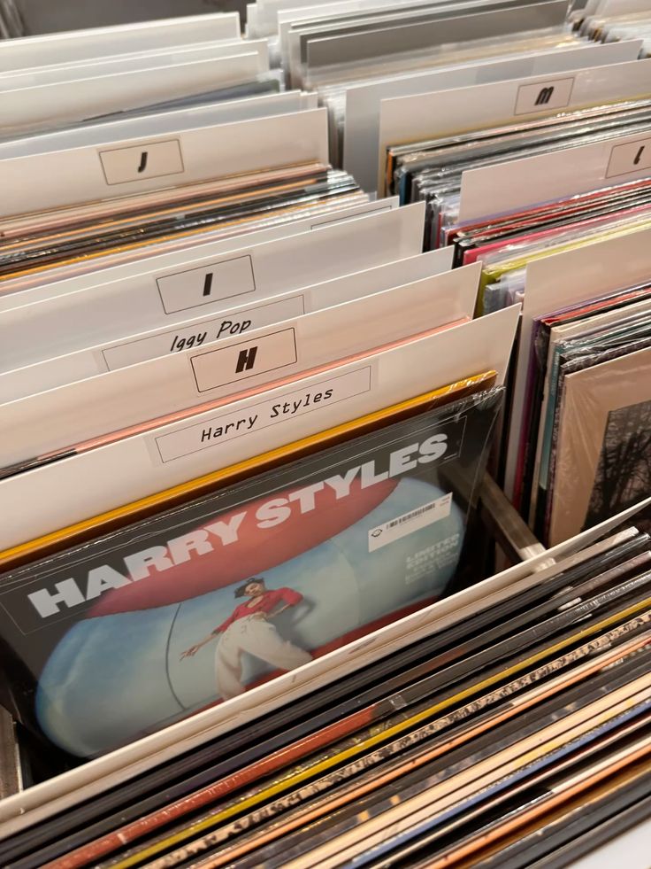 Harry_3 🍒 Vinyl records shelf with albums organized alphabetically, featuring Iggy Pop and Harry Styles. Music collection in a record store. | Sky Rye Design Vinyl records shelf with albums organized alphabetically, featuring Iggy Pop and Harry Styles. Music collection in a record store.