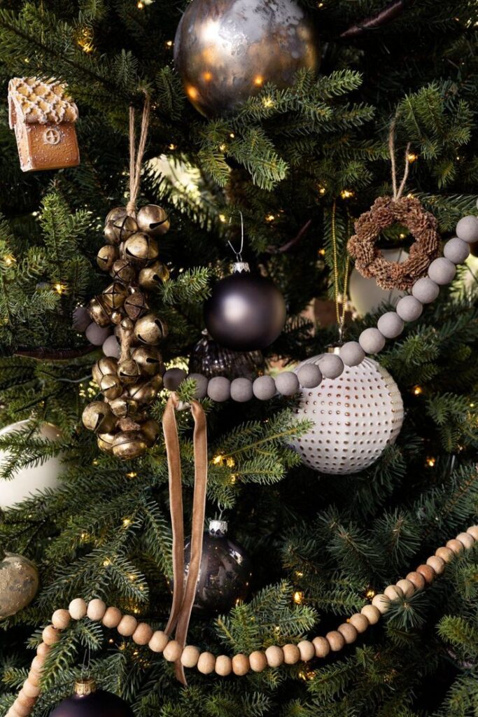 Festive Christmas tree with rustic ornaments, wooden beads, bells, and baubles, creating a cozy and elegant holiday atmosphere.