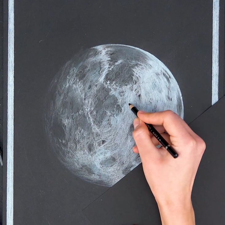 Hand drawing a detailed moon sketch on black paper using a white pencil, showcasing realistic lunar surface textures and craters.