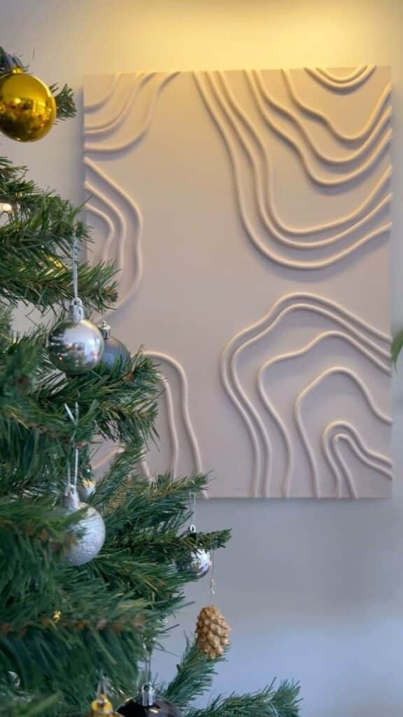 Decorated Christmas tree with abstract wall art in the background.