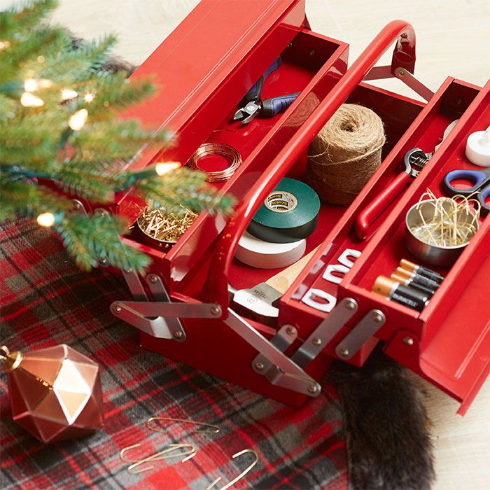 Keep Christmas ornament hangers twine scissors batteries and tape organized in a repurposed toolbox_ Red toolbox filled with crafting supplies and tools on a plaid surface, next to a Christmas tree and ornaments. | Sky Rye Design Red toolbox filled with crafting supplies and tools on a plaid surface, next to a Christmas tree and ornaments.