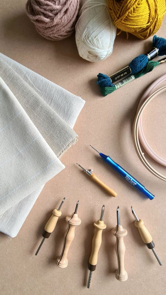 Punch needle tools and supplies with colorful yarn, embroidery fabric, and hoops, perfect for creative embroidery and crafting projects.