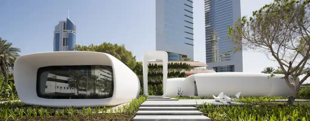Killa-Design-Office-of-the-Future-Hero Futuristic white 3D-printed building with modern skyscrapers in the background amidst greenery and blue skies. | Sky Rye Design Futuristic white 3D-printed building with modern skyscrapers in the background amidst greenery and blue skies.