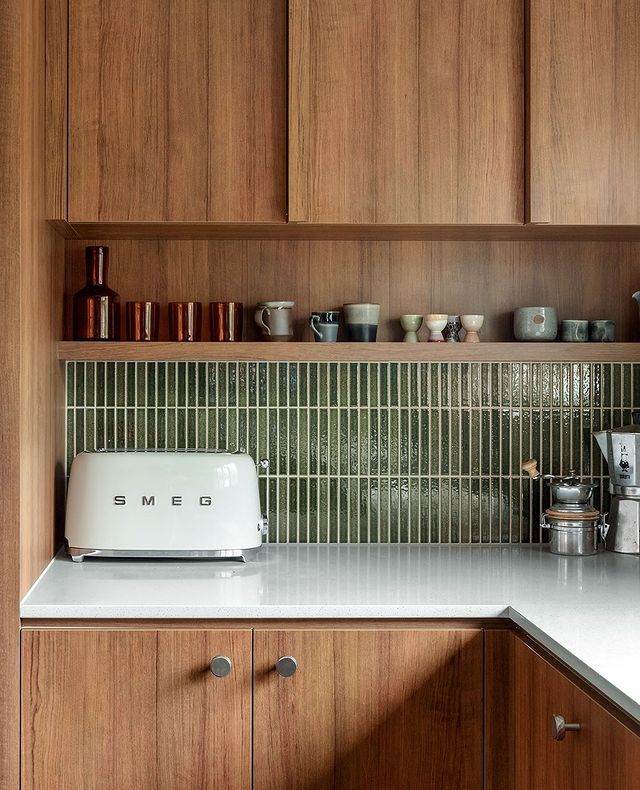 Laminex AU on Instagram_ _Mid-Century Magic_ _ If youre wanting to inject a bit of old-school glamour into your kitchen take a page out of mjharrisgroups book__ Sleek kitchen with a white SMEG toaster, green tile backsplash, and wooden cabinets, featuring modern design elements. | Sky Rye Design Sleek kitchen with a white SMEG toaster, green tile backsplash, and wooden cabinets, featuring modern design elements.