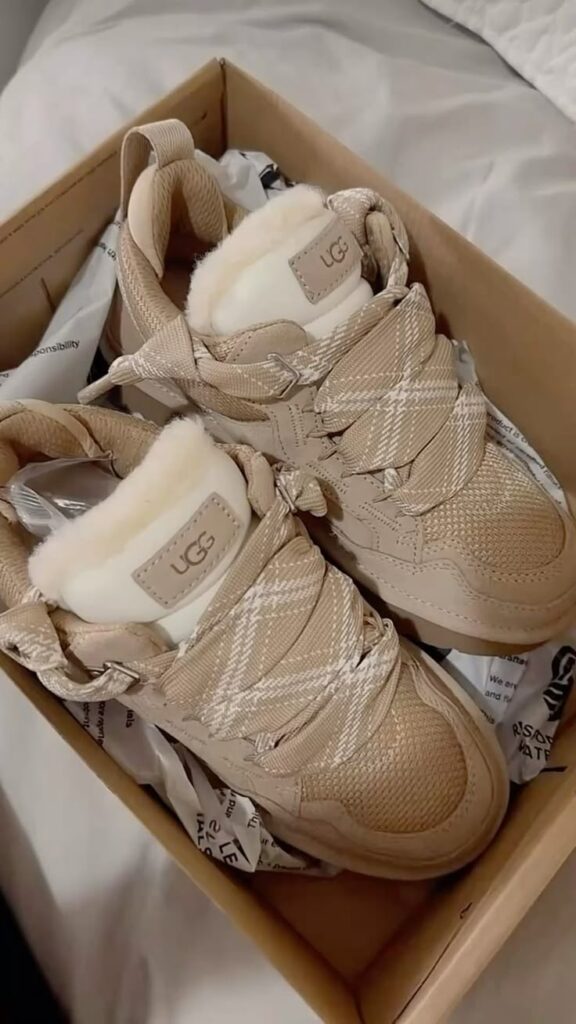 Les UGG 🩷🩶 Beige UGG sneakers with plaid accents in a box on a white background, showcasing cozy fur lining and stylish design. | Sky Rye Design Beige UGG sneakers with plaid accents in a box on a white background, showcasing cozy fur lining and stylish design.