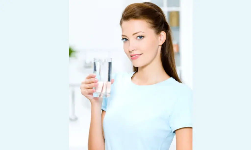 List-of-Factors-to-Take-Into-Account-When-Buying-a-Water-Purifier-1_5f0e96fe-c009-4feb-a361-0fb84831ec0b-937997 A woman in a blue shirt holding a glass of water, promoting hydration and healthy living. | Sky Rye Design A woman in a blue shirt holding a glass of water, promoting hydration and healthy living.
