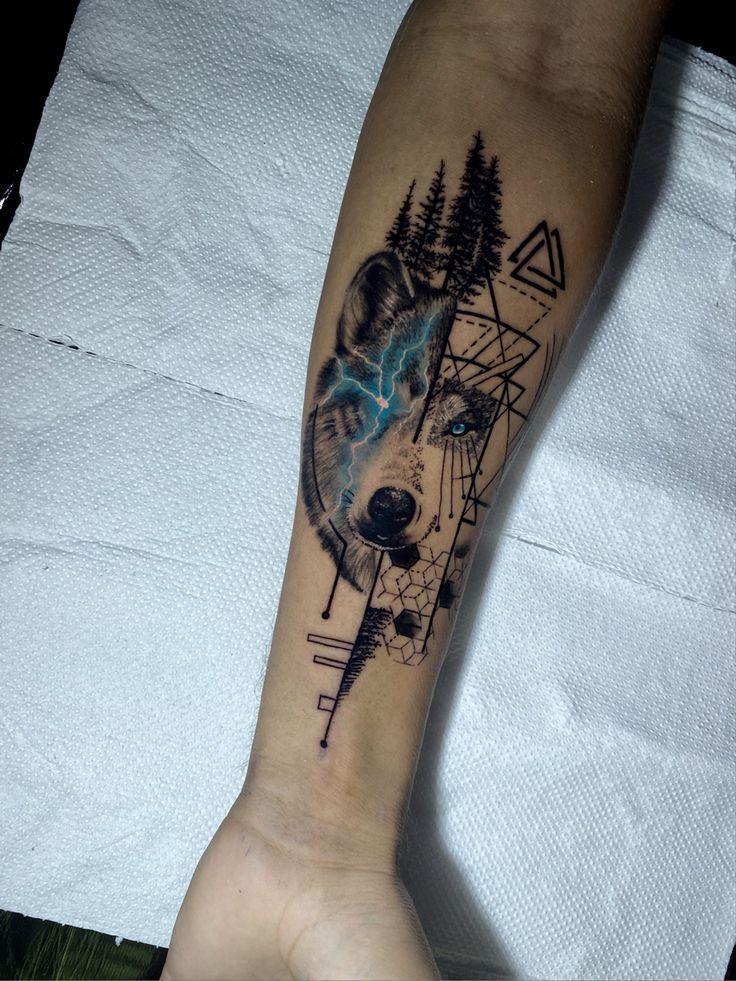 Lobo com raio azul no olho Unique wolf tattoo on forearm with geometric patterns and trees, highlighting artistic body ink design. | Sky Rye Design Unique wolf tattoo on forearm with geometric patterns and trees, highlighting artistic body ink design.