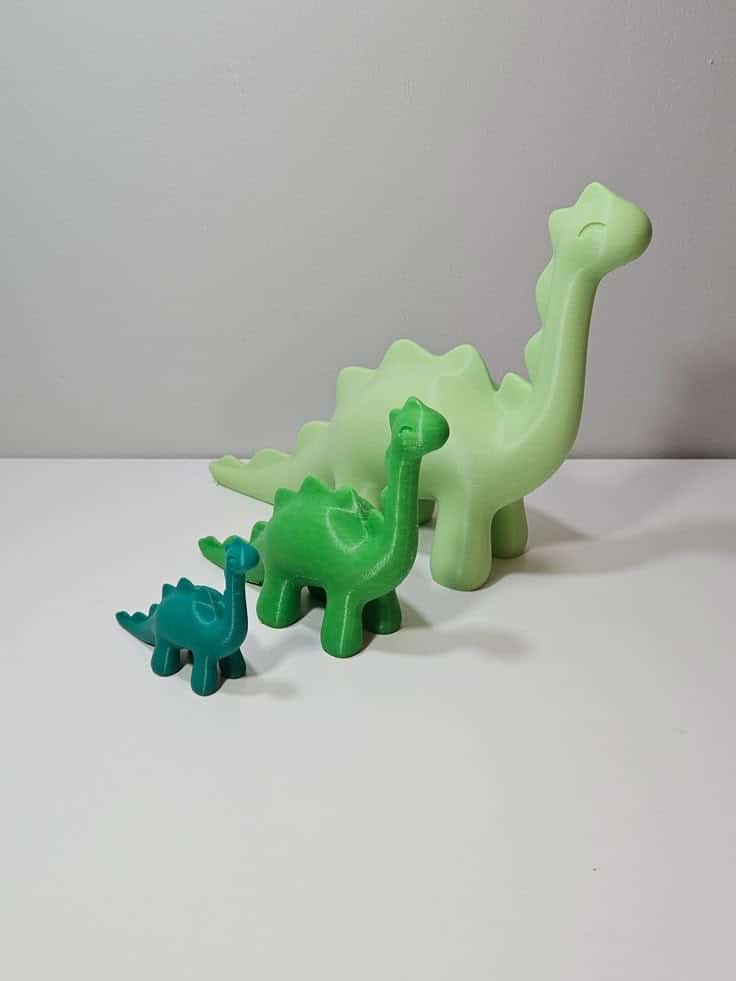 Three colorful dinosaur figurines in varying sizes on a white surface, perfect for playful home decor or children's toys.