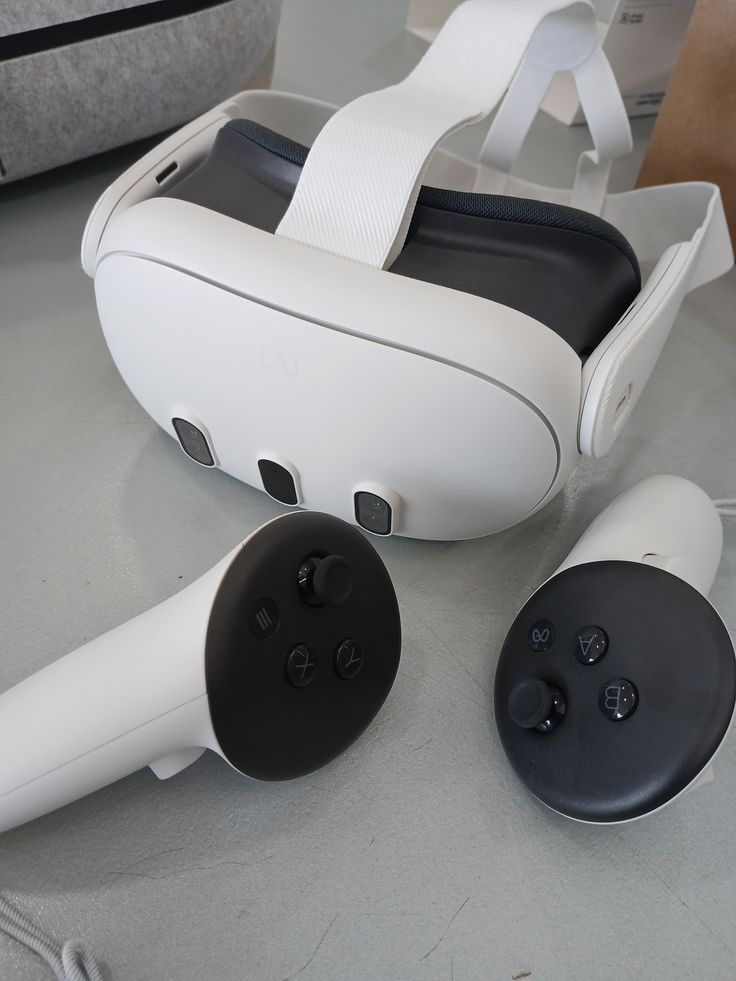 White virtual reality headset with two handheld controllers on a table, showcasing modern VR gaming technology and design.