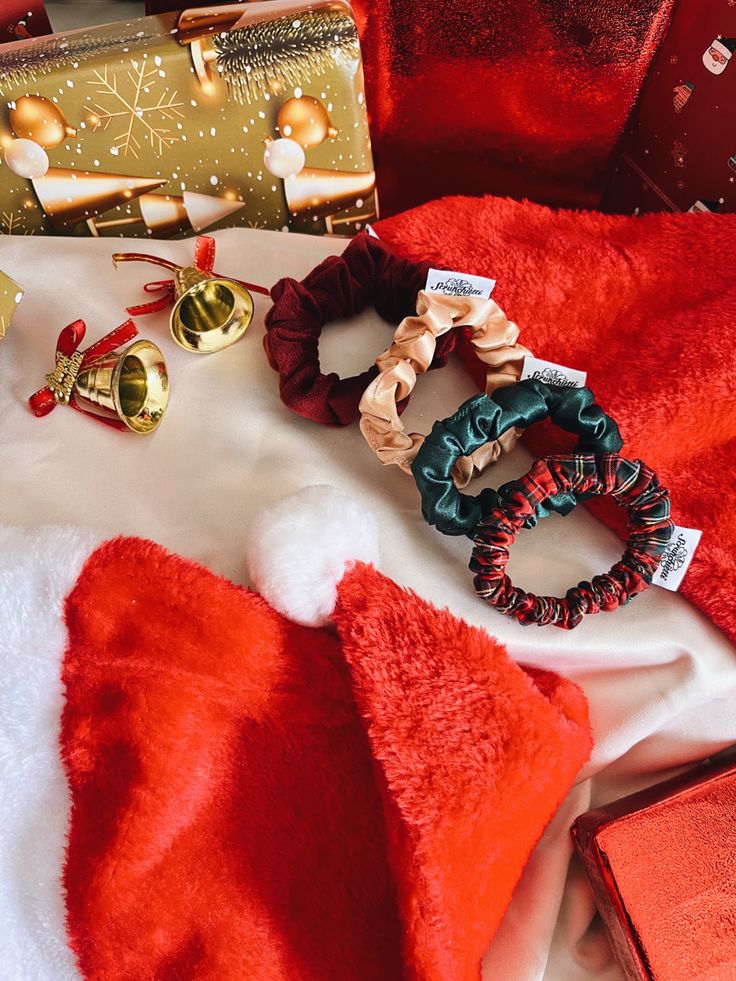 Mini scrunchies Christmas festive gift ideas Festive holiday flat lay with Santa hat, wrapped gifts, colorful scrunchies, and Christmas bells on a plush red and white fabric backdrop. | Sky Rye Design Festive holiday flat lay with Santa hat, wrapped gifts, colorful scrunchies, and Christmas bells on a plush red and white fabric backdrop.