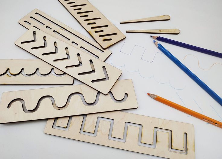Wooden line tracing templates and colored pencils on a white surface, perfect for crafts, tracing activities, and educational projects.