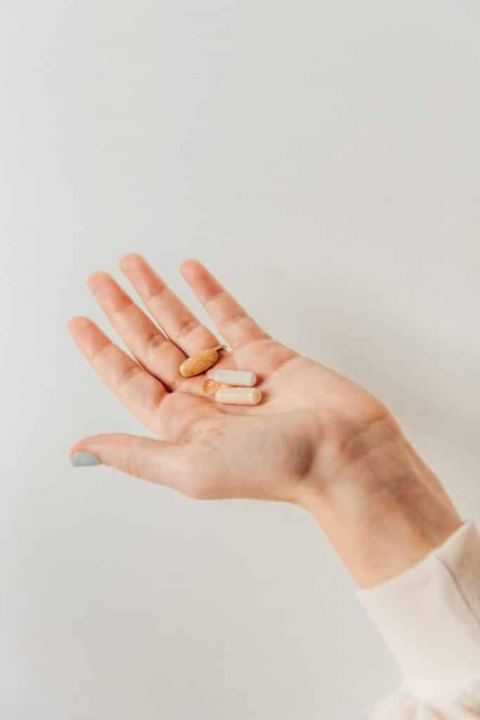 NY RESOLUTION Hand holding various pills and capsules against a neutral background. Ideal for health and wellness topics. | Sky Rye Design Hand holding various pills and capsules against a neutral background. Ideal for health and wellness topics.
