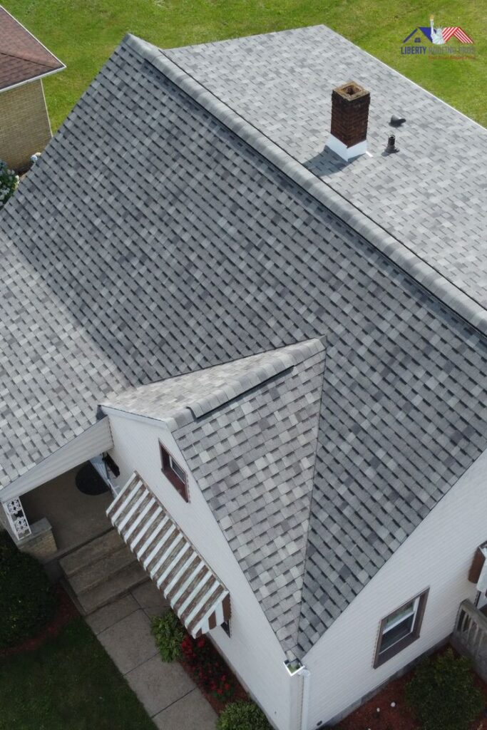 Not all shingles are built for every weather Aerial view of a house with new gray shingle roof and chimney, surrounded by green lawn. | Sky Rye Design Aerial view of a house with new gray shingle roof and chimney, surrounded by green lawn.