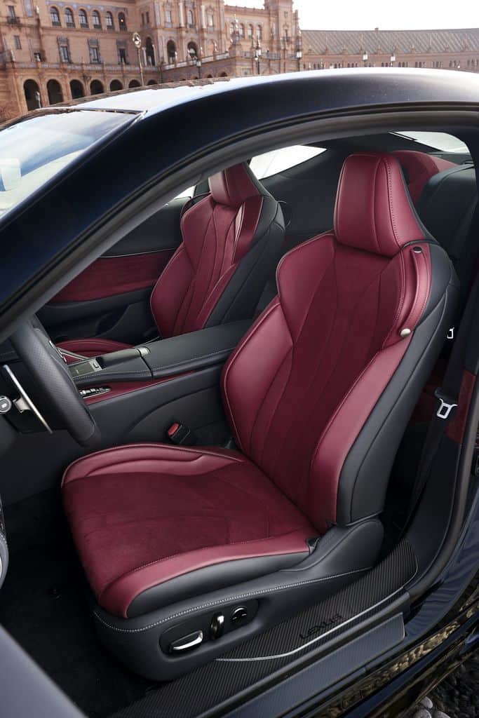 Luxurious car interior featuring sleek red leather seats in a modern vehicle with an elegant exterior backdrop.