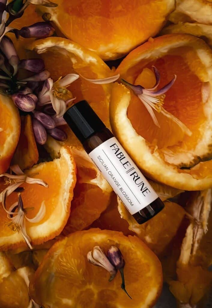 PERFUME OIL - Winter Balsam Perfume bottle labeled Sicilian Orange Blossom surrounded by vibrant orange slices and blossoms. Enhanced fragrance essence. | Sky Rye Design Perfume bottle labeled Sicilian Orange Blossom surrounded by vibrant orange slices and blossoms. Enhanced fragrance essence.
