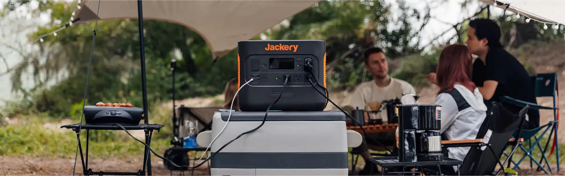 PPS_FAQ_PC_1920x Portable power station at campsite with people relaxing around it, powering small electronics and cooking appliances. | Sky Rye Design Portable power station at campsite with people relaxing around it, powering small electronics and cooking appliances.