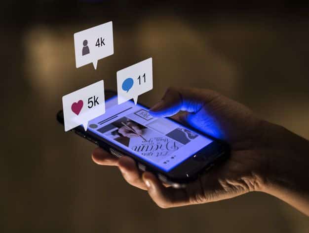 Hand holding smartphone with social media notifications: 4k followers, 5k likes, 11 comments. Engaging online presence, digital networking.