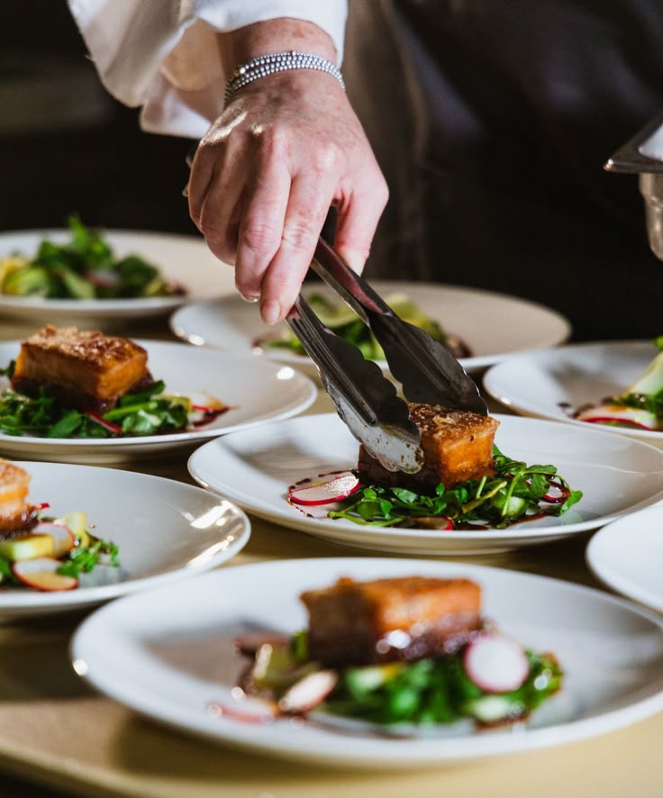 Private Dining under the stars Chef plating gourmet dishes with precision using tongs, showcasing culinary art with fresh greens and neatly arranged ingredients. | Sky Rye Design Chef plating gourmet dishes with precision using tongs, showcasing culinary art with fresh greens and neatly arranged ingredients.