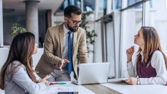 Reducing Small Business Risks With Smarter Data Practices Business meeting with three professionals discussing a project around a laptop in a modern office setting. | Sky Rye Design Business meeting with three professionals discussing a project around a laptop in a modern office setting.