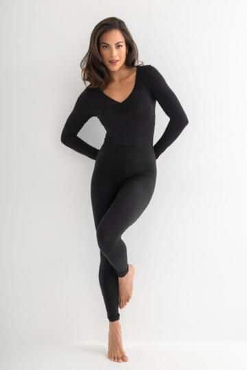 Woman in sleek black bodysuit poses confidently, showcasing elegant fashion style against a minimalist white background.