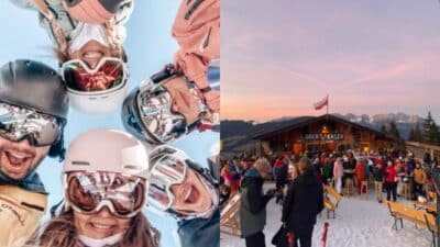 Group of smiling skiers taking a selfie in the snow; busy après-ski scene at a mountain chalet under a pink sunset sky.