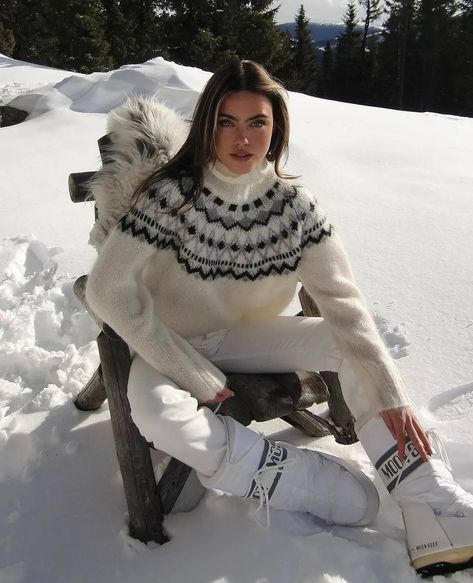 Woman in a cozy knit sweater and snow boots sitting on a snowy landscape, enjoying a winter day outdoors.