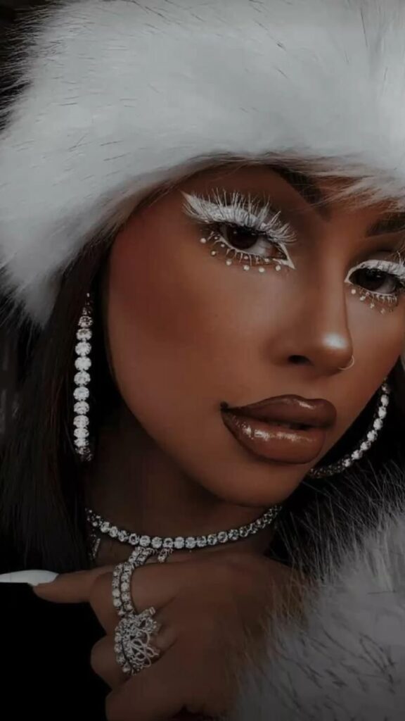 Glamorous woman wearing sparkling jewelry, dramatic white eye makeup, and a stylish white fur hat. Elegant and bold fashion statement.