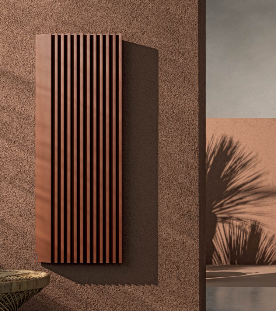 Vertical radiator on a textured terracotta wall with shadow of a palm plant, featuring minimalist design and warm earth tones.