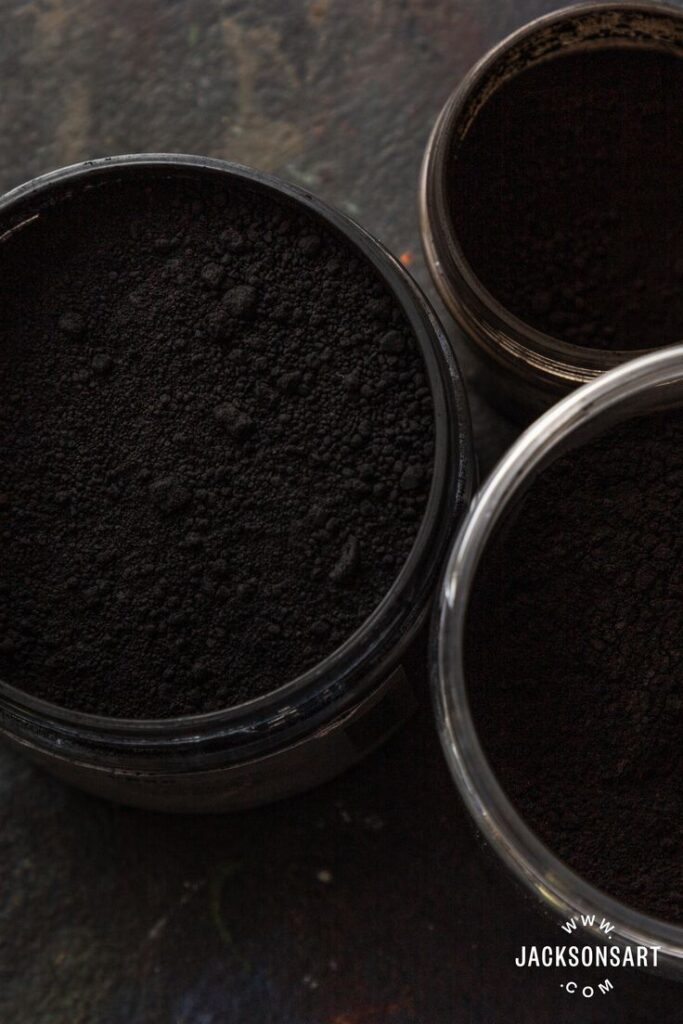 Containers of dark powder, possibly black pigment, viewed from above. Ideal for art projects or creative use.