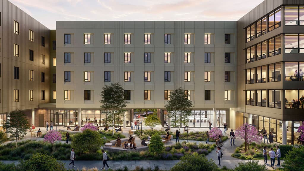 Modern courtyard with people relaxing and socializing around landscaped greenery, surrounded by a contemporary multi-story building at dusk.