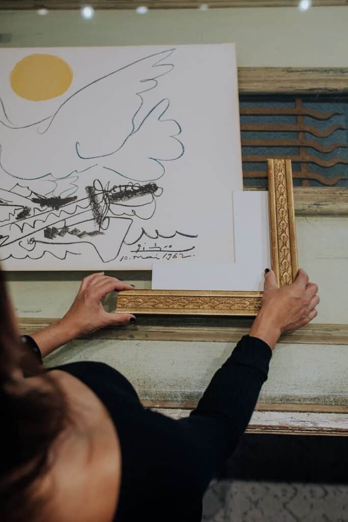 Person framing a dove drawing with gold frame, showing art presentation and creative design.