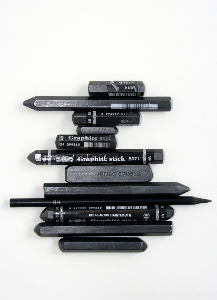 Assorted black graphite sticks and pencils on a white background, ideal for artists and sketching enthusiasts.