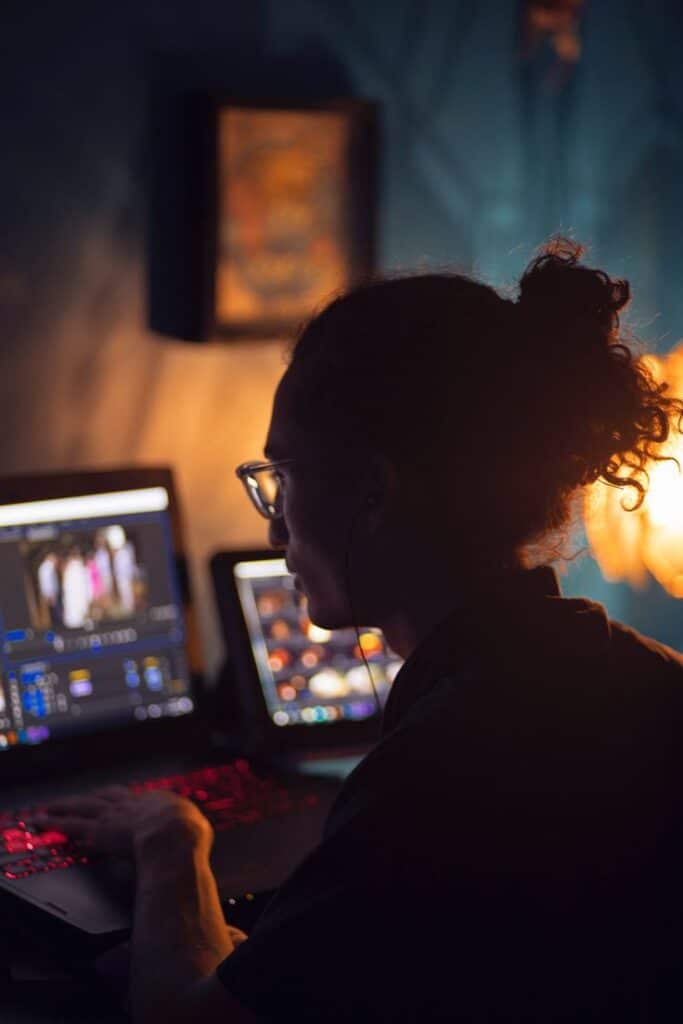 Using Macros to Automate Video Editing - FilterGrade Person editing video on dual monitors in a dimly lit room. | Sky Rye Design Person editing video on dual monitors in a dimly lit room.