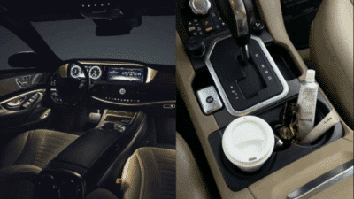 Luxurious car interior with illuminated dashboard, gear shift, coffee cup, and lotion in cup holders.