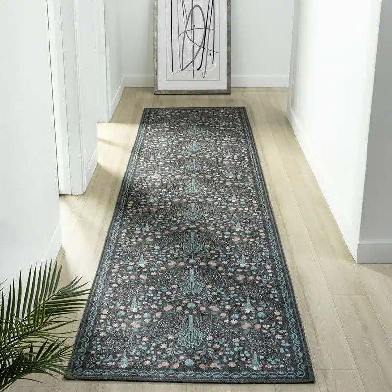 Ornate hallway runner rug on a wooden floor next to abstract wall art and plant.