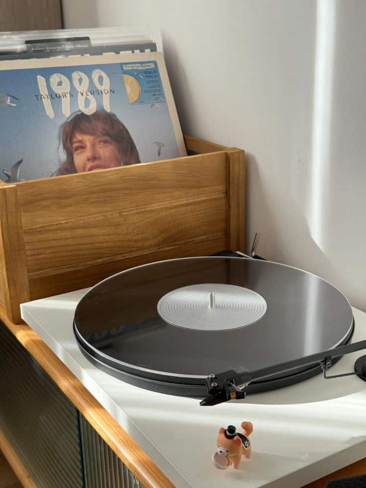 Vinyl record mats Turntable with vinyl records, including a pop album displayed in a cozy wooden crate, lit by sunlight. | Sky Rye Design Turntable with vinyl records, including a pop album displayed in a cozy wooden crate, lit by sunlight.