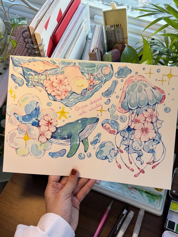 Washitape practice washitape watercolor Hand holding watercolor art featuring whimsical ocean scene with whales, jellyfish, flowers, and pastel colors. | Sky Rye Design Hand holding watercolor art featuring whimsical ocean scene with whales, jellyfish, flowers, and pastel colors.