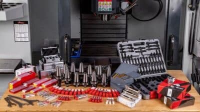 Various CNC machine tools and accessories displayed on a table in front of the machine.