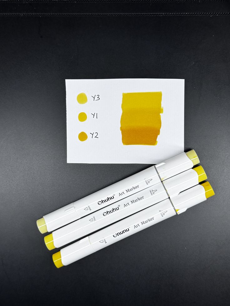Yellow Ohuhu art markers with sample swatches on paper, showing shades Y3, Y1, and Y2.