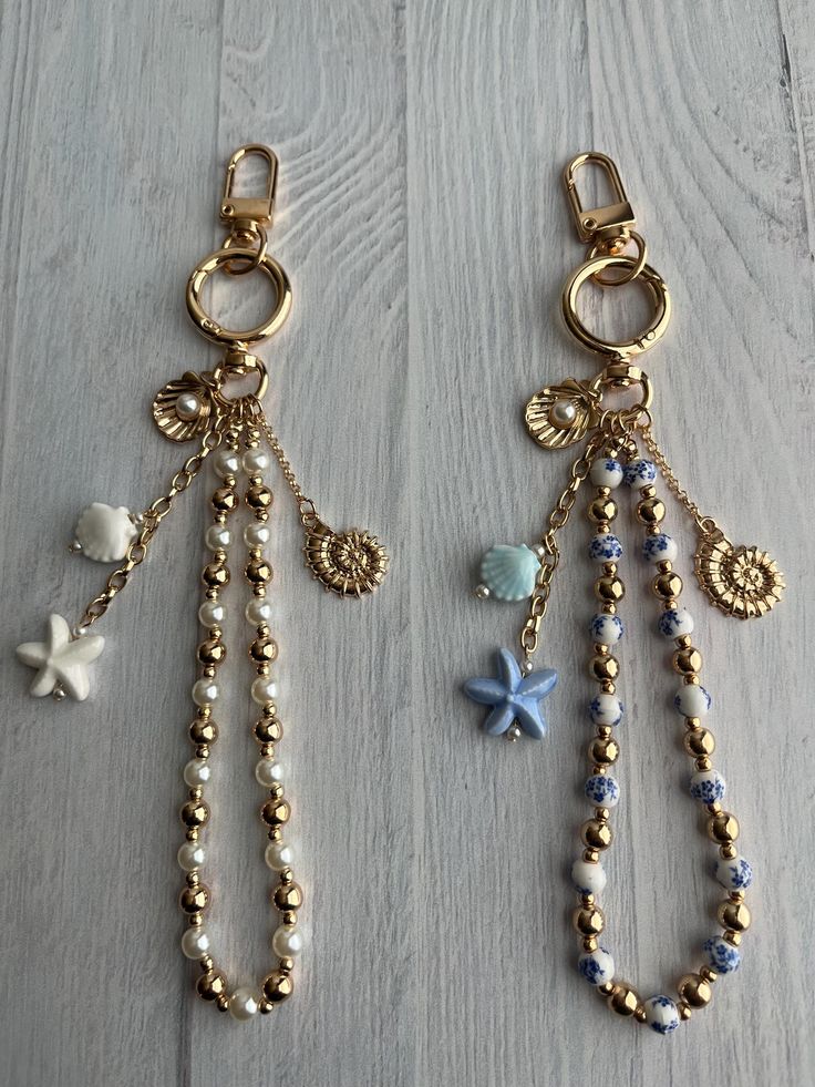 Gold bead keychains with starfish, shells, and charms on a light wooden surface.