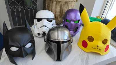 Assorted character masks, including a superhero, sci-fi warrior, and animated creature, displayed on a table.