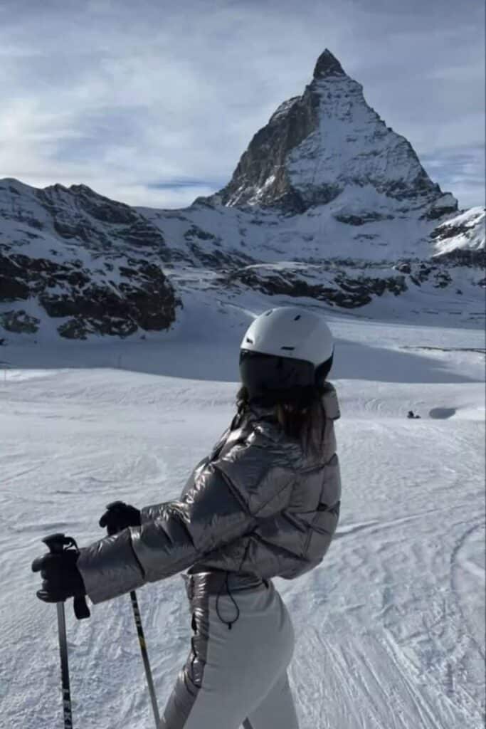 Skier in metallic jacket enjoying snowy slope with Matterhorn peak in the background on a clear day.
