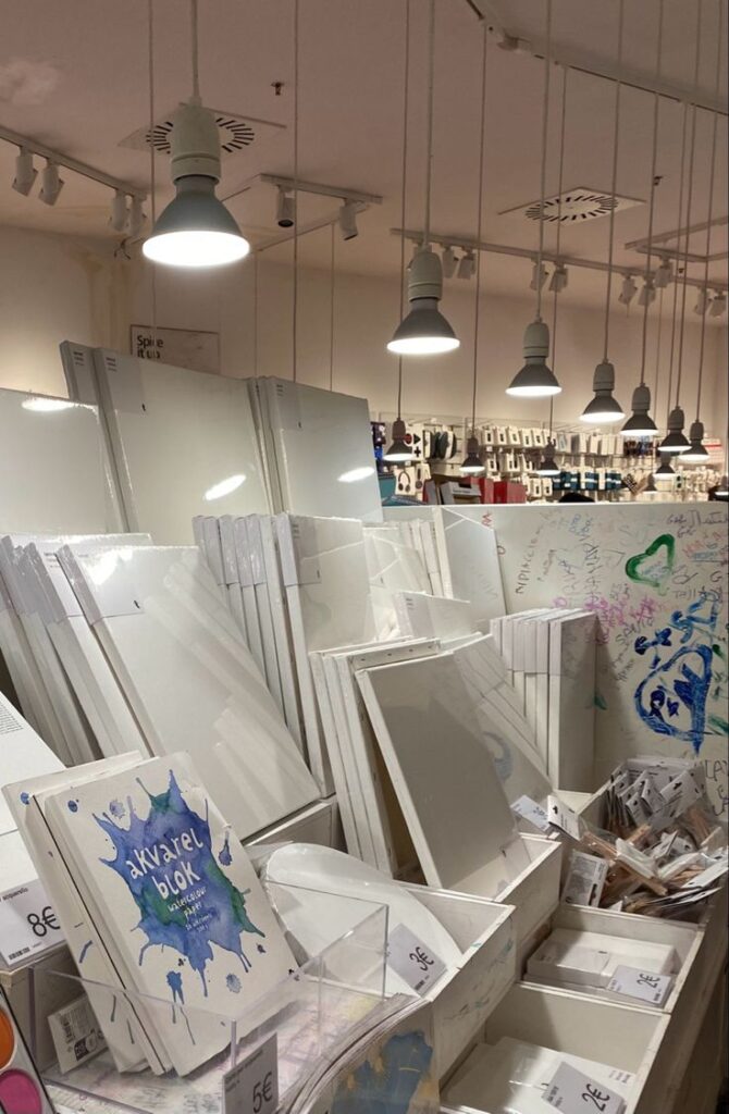 Art supplies store with various canvases, watercolor paper, and painting tools under bright lighting.