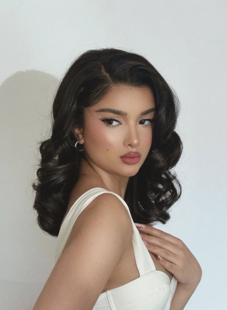 b0fd86b48b72c53b59a11d633cfa74a3 Woman with dark wavy hair and glamorous makeup poses in a white outfit against a neutral background. Fashion and beauty. | Sky Rye Design Woman with dark wavy hair and glamorous makeup poses in a white outfit against a neutral background. Fashion and beauty.