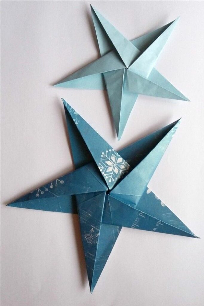 Two blue origami star decorations on a white background, showcasing intricate paper folding art for crafts and DIY projects.