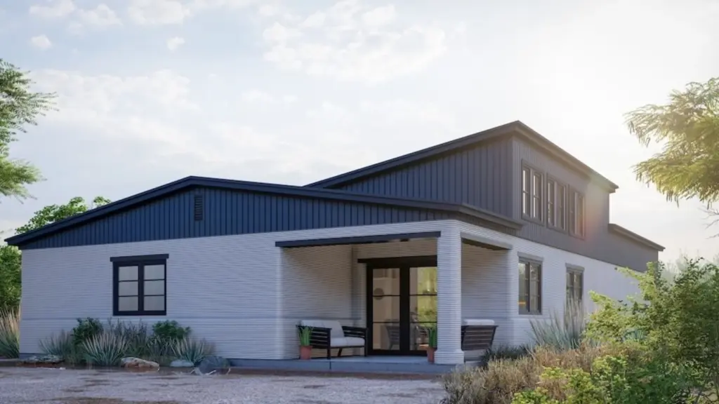 Modern single-story house with dark blue siding and large windows, surrounded by desert landscaping under a clear sky.